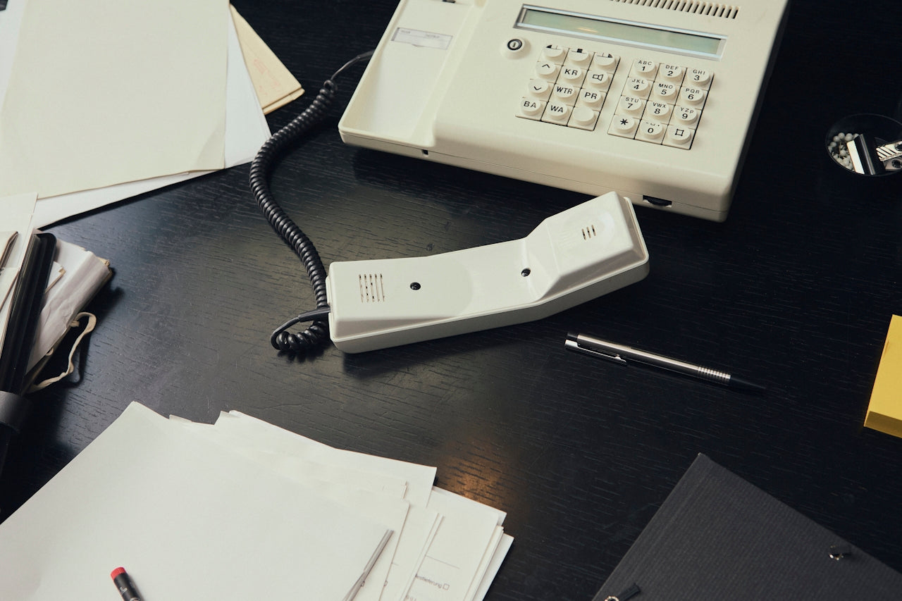 Old telephone on a desk with papers and a pen