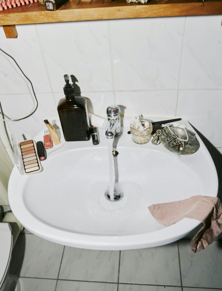 White sink with various items on a tiled bathroom wall